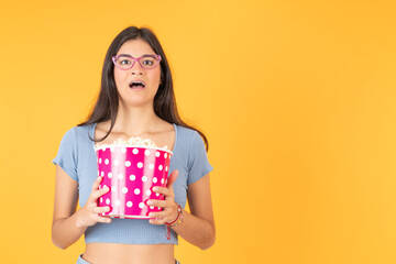 Woman with a terrified expression holding a bag of popcorn