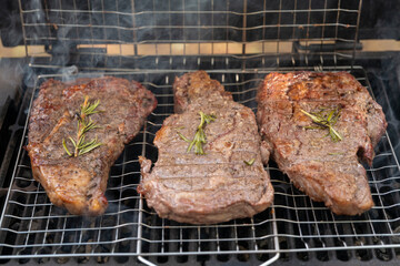 tasty steak on a bbq grill with smoking smoke and fire and glowing coals. High quality photo