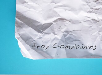 Crumpled paper on blue background with text Stop Complaining - concept of changing habit of focus negativity, minimize complaining and maximize optimism
