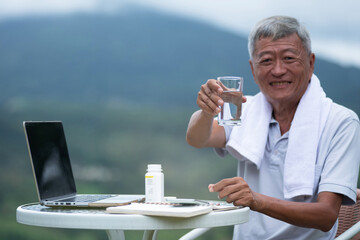 Asian old man sat in the atmosphere of the mountain view, persuaded to drink clean water, looking...