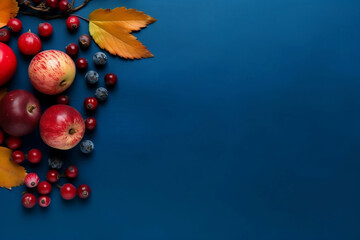 Fototapeta premium Apples and berries autumn harvest and leaves on navy blue background, top view, Thanksgiving and Halloween autumn background.