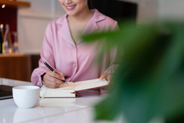 Female entrepreneur write data in notebook while working about strategy new startup in home office