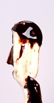 4K footage vertical video front view CU Time-lapse, Ice cream sticks topped with melting chocolate on a white background.