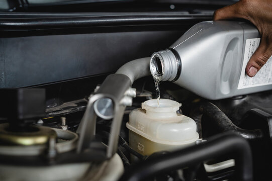 Auto mechanic adding brake fluid into the brake fluid reservoirs.