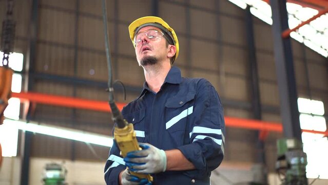 Caucasian senior industrial engineer controlling a heavy duty crane in the factory close up. A professional contractor using remote control to control crane and lift system in the factory.