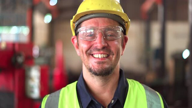 Portrait footage of smart - good looking professional engineer or technician in factory smiles to camera. 
