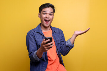 Happy excited Asian man showing surprise expression with open arms while holding smartphone