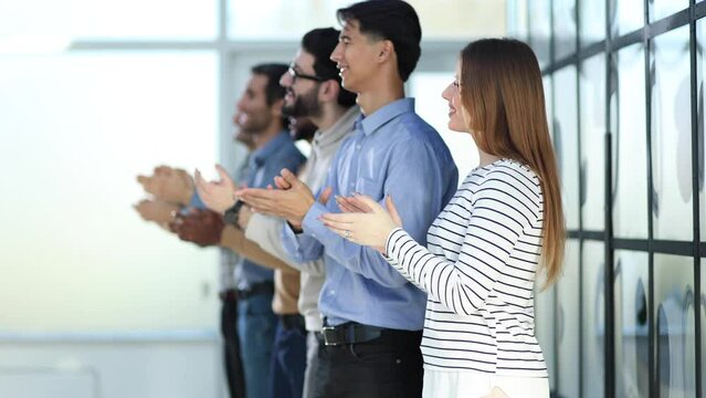 A group of people standing in a row clapping their hands