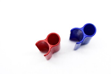 The two red and blue marker caps made of plastic appear photographed on the isolated white background