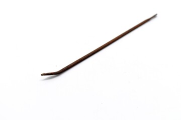 This mattress thread needle made of metal looks rusty and was photographed on the isolated white background