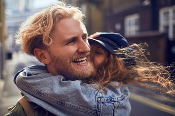 Young caucasian couple hugging and embracing each other on a sidewalk in the city