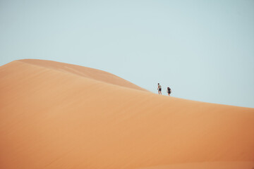 People climbing Erg Chebbi dunes in Sahara Desert, Merzouga, Morocco