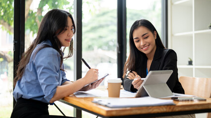 Two businesswomen are discussing work and planning a financial project at a table in the office