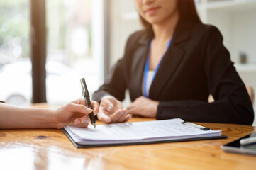 A client signing a contract agreement or filling out a form in front of a businesswoman