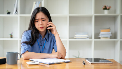 A stressed Asian businesswoman is having a serious conversation over the phone