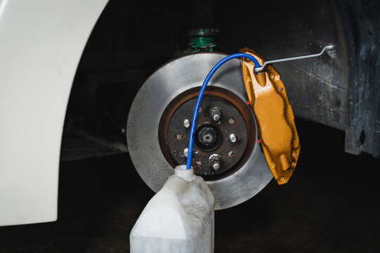 Car brake fluid bleeding service in garage service shop.