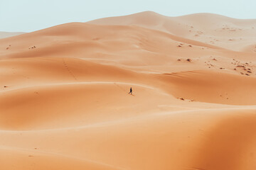 Fototapeta na wymiar Incidental local berber man wandering through Sahara Desert Merzouga, Morocco