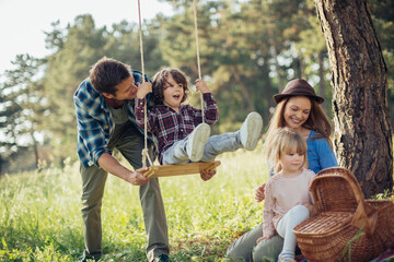 Young caucasian family having a picnic on a grassy field in nature