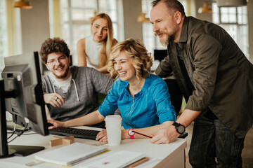 Diverse group of colleagues engaging in a discussion over computer work in a office
