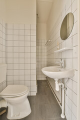 a bathroom with white tiles and black gre flooring on the walls there is a mirror above the sink