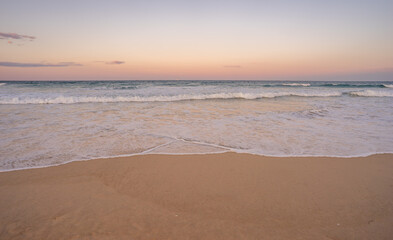 The surf and colorful sky at dusk along Kawana beach on the Sunshine Coast, Queensland, just before the Blue Moon rises above the horizon along the east coast of Australia 2023