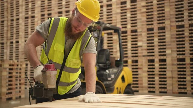 Young workers working in a woodworking factory, Using a nailing machine to assemble wooden pallets