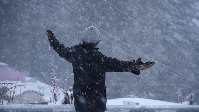 People, season and christmas concept - happy young man in winter forest turning around, Auli, uttarakhand, india.
