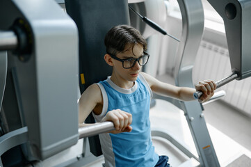 Fototapeta na wymiar Skinny preteen nerd trying to be strong and healthy training at gym