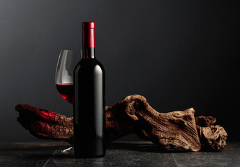 Red wine and old weathered snag on a black stone table. - obrazy, fototapety, plakaty