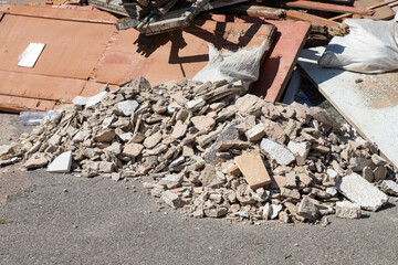 Construction waste. A pile of broken concrete debris and rubble. Demolition rubble. Junk, garbage piled up near the building. Street scene. Close-up.