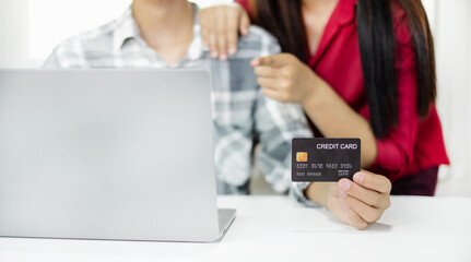 E-commerce Concept. Happy couple holding credit card enjoying doing online shopping and using laptop enter their card number in-app to purchase and payment in internet store