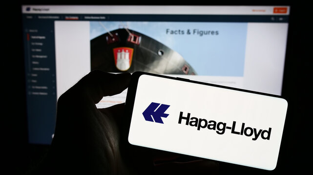 Stuttgart, Germany - 08-28-2023: Person holding smartphone with logo of German shipping company Hapag-Lloyd AG on screen in front of website. Focus on phone display.