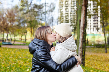 Hello october. Mother and daughter are walking in the autumn city park. Parent and little child having fun outdoors