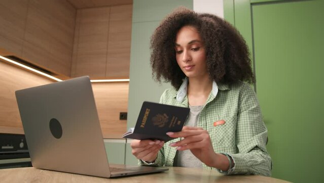 Woman Typing on Laptop Holding US Passport. Black female working holding US passport document.