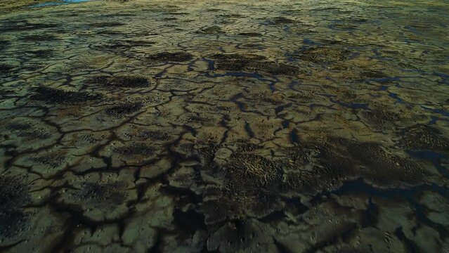Dark black cracks of toxic oil asphalt waste in refuse pit lake, aerial dolly