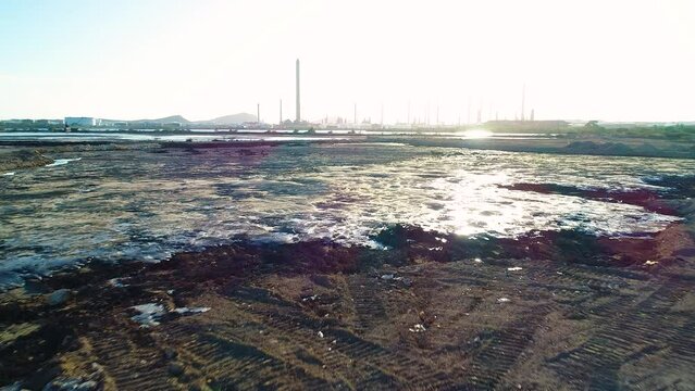 Low flying drone aerial above black tar bubbles from toxic asphalt lake