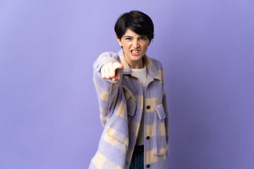 Woman with short hair isolated on purple background frustrated and pointing to the front