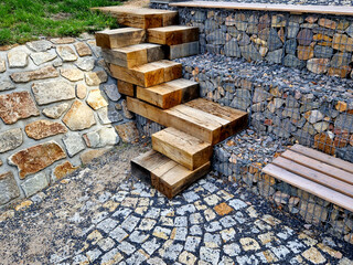 how to solve the steep entrance to the water on the dam. oak beams stacked and screwed together in a chaotic direction on top of each other. gabion slope go down the stairs - obrazy, fototapety, plakaty