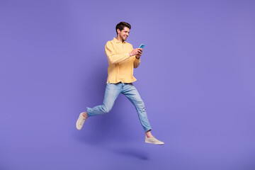 Fototapeta na wymiar Full length size body photo of jumping funky guy browsing new modern smartphone social media marketer isolated on violet color background