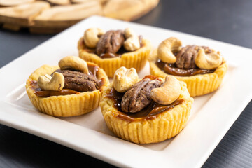 tartlet with caramel and nuts on a white plate. pecan. cashew.food concept. dessert. bakery. diet