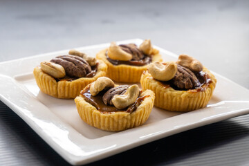 tartlet with caramel and nuts on a white plate. pecan. cashew.food concept. dessert. bakery. diet