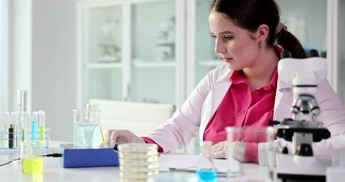 Laboratory woman worker works with samples and liquid in premise. Female expert in robe prepares for lab examination concept slow motion