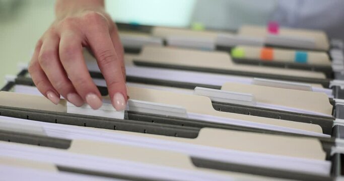Female worker sorts through cardboard with files in archive. Corporate documents stored on shelf in office. Business activity cases concept slow motion