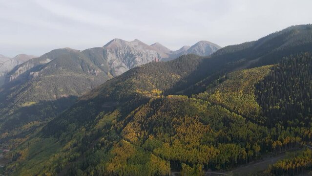 A high-flying, slow moving drone shot, over mountain peaks of the Rocky Mountains, near Telluride, Colorado, on a sunny day in the Fall season.