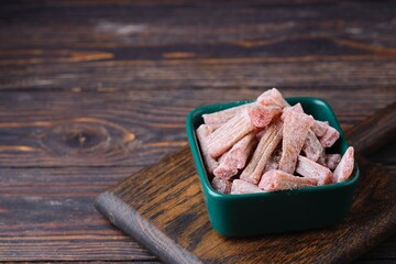 Candied rhubarb, sprinkled with powdered sugar, in a ceramic plate on a purple wooden background. Preparations, conservation. Rhubarb recipes.