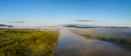 Obraz premium Morning fog and mist over river through green Northern Hokkaido landscape