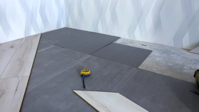 Laying the substrate under the laminate in a rectangular way. Repairs. The handyman lays a noise-absorbing underlay under the laminate in advance, Construction work. Renovation of a new house. 4k