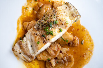 top close up take of a croaker fish dish cooked in the oven with potatoes and species like rosemary and black pepper