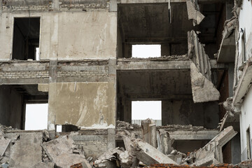 A destroyed building in close-up with a pile of concrete debris, slabs and piles in the foreground. Background