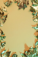 Vertical image of metallic gold autumn leaves with copy space on orange background